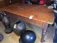 Full view of wood table with visible stains and cracks. Shows the table's top surface and legs.