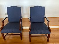 Photo of two blue formal living room arm chairs with pinpoint pattern placed side by side on wooden floor, showing front view.
