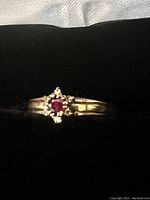 Front view showing the round ruby set in prongs on the polished yellow gold band.