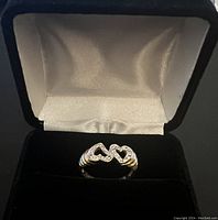 Front angle view of the 14K yellow gold double heart ring with diamond accents presented inside a black velvet and white satin ring box.