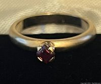 Close-up front view showing small square garnet mounted on gold tone band.