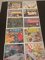 Top view of 10 comics arranged in two rows of five on a black surface, all comics are bagged and boarded, showing cover art and titles.