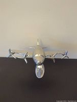 Front-facing view of the aluminum airplane model showing four propellers and rounded nose.