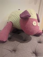 Plush sheep angled view showing pink limbs and ears, cream cable-knit body, and button eyes.