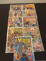 Top-down photo showing all 9 comics spread in two rows, featuring X-Factor and Excalibur comic covers clearly visible.