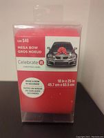 Front view of the Celebrate It Mega Bow box showing brand, size, and usage information with image of a car decorated with the bow.
