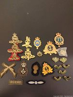 Full layout of the lot showing many military badges and patches on black background including brass pins, fabric patches, chevrons, and anchor insignias.