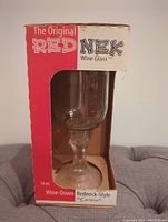 Original red and white branded product box with visible window showing transparent Mason jar shaped wine glass on pedestal inside.