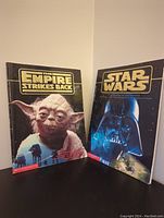 Front view of two 1997 Scholastic Star Wars books: The Empire Strikes Back with Yoda, and Star Wars with Darth Vader.