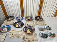 Photo showing all plates laid out with their certificates of authenticity, including both larger and smaller collector plates.
