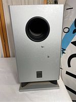 Silver Onkyo powered subwoofer front view showing port and base stand.