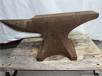 Full view of anvil on wooden pallet showing overall shape, horn, flat face, base and heavy cast construction