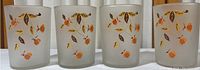 Four frosted glass tea glasses with orange flower and brown leaf design arranged in a row