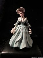 Front view of the full Florence Ceramics figurine depicting a woman named Julie wearing a flowing dress and hat, holding a book and purse.
