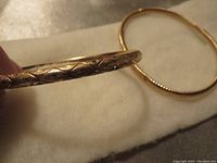 Close-up showing the dented hollow gold hoop earring with visible worn pattern.