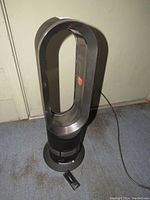 Full front view of one Dyson HP02 Pure Hot + Cold Link air purifier showing its bladeless oval loop amplifier on circular base with power cord and remote on floor.