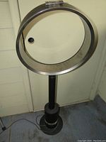 Dyson AM08 black bladeless pedestal fan full view showing the circular air loop and pedestal stand on a carpeted floor.