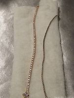 Two tennis bracelets placed on white fabric, showing different metal tones and clasp designs