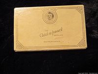 Closed antique Add-a-pearl necklace box with infant portrait and label on the lid.