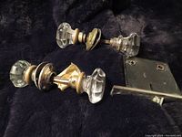 Pair of antique clear glass 8-sided door knobs with star center design, threaded on spindles with attached metal lock mechanism.