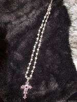 Full view of the necklace laid out on black fabric, showing chain and cross pendant.