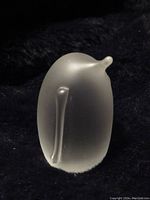 Photo showing the back and side view of a frosted crystal penguin figurine on dark fabric.
