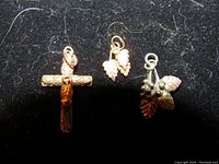 Three Black Hills Gold charms on black background including cross and two grapevine charms
