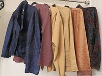 Five Coldwater Creek women's business jackets hanging on a rack showing various colors and textures including navy blue, dusty rose, beige, and a dark multicolor floral pattern.