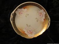 Top view of the porcelain bowl displaying pastel pink roses and gold rim with handles