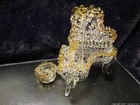 Front angle of clear hand blown glass baby grand piano and matching seat with yellow trim on black fabric background.