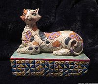 Side view of the stylized cat figurine showcasing detailed colorful patchwork patterns and geometric shaped base.