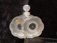 Frosted crystal Lalique perfume bottle shaped like two flowers with detailed petals and centers, showing front view with stopper on top.