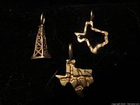Three 14K gold charms displayed on black background: Texas state solid charm with raised pattern, hollow Texas state outline charm, and oil rig charm.