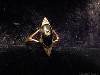 Photo showing close-up of the vintage 14K gold ring with an elongated black stone and diamond accents on a dark background