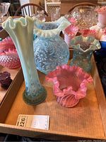 Photo showing full lot including floral pattern blue pitcher, tall green vase with ruffled top, pink vases, and pink footed bowl on wooden tray