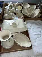 Box of mixed porcelain pieces including vases, bowls, a clock, covered server, cross, and plates.
