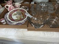 Overview of boxed china plates with scenic and floral patterns, Spode egg cup, Mason's and Johnson Bros. creamer and sugar bowl, and clear cut glassware.