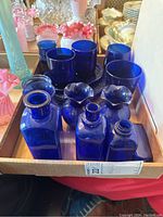Photo of cobalt blue glassware set including bottles, glasses, dishes, and plates arranged in an open box.