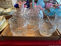 Five clear crystal pieces displayed in a cardboard tray, including three bowls and two lidded jars with detailed cut patterns.