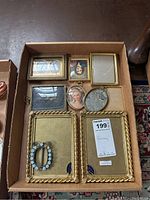 Top view of nine assorted picture frames in box on floor.