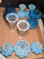Overview of lot showing all glass items including three blue overlay perfume bottles with clear stoppers, two white opalescent hobnail vases, a blue crackled glass pitcher, and one smaller blue glass pitcher.