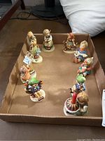 Group view of the ten Goebel Hummel figurines arranged in a cardboard tray showing various poses and detailed coloring