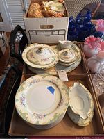 Full view of boxed set including plates, bowls, covered serving dishes and gravy boat with underplate, all with floral and gold pattern on Noritake Delphina china.