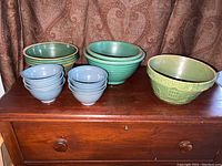 Full overview of all pottery bowls grouped by color and size on wooden chest