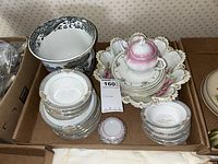 Photo showing grouped plates, sugar bowl, serving dish, and small bowls stacked in a box.