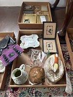 Overview of lot items including trinket dish, ceramic jug, bird figurine, glass drawer pulls, small framed pieces, and boxes containing small items, on a patterned rug