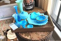 Overview photo of all blue glass vases, bowls, and dishes arranged in a cardboard box and surrounding area