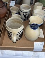 Box containing Williamsburg Pottery pitchers and mugs, showing color and design details
