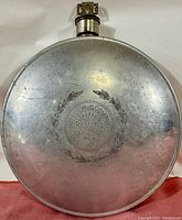 Front view of the 1915 aluminum canteen showing the embossed United Drug Company and Palco Radiator circular emblem with laurel wreath.