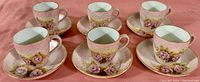 Front angled view of six demitasse cups placed on matching saucers, showing design and condition
